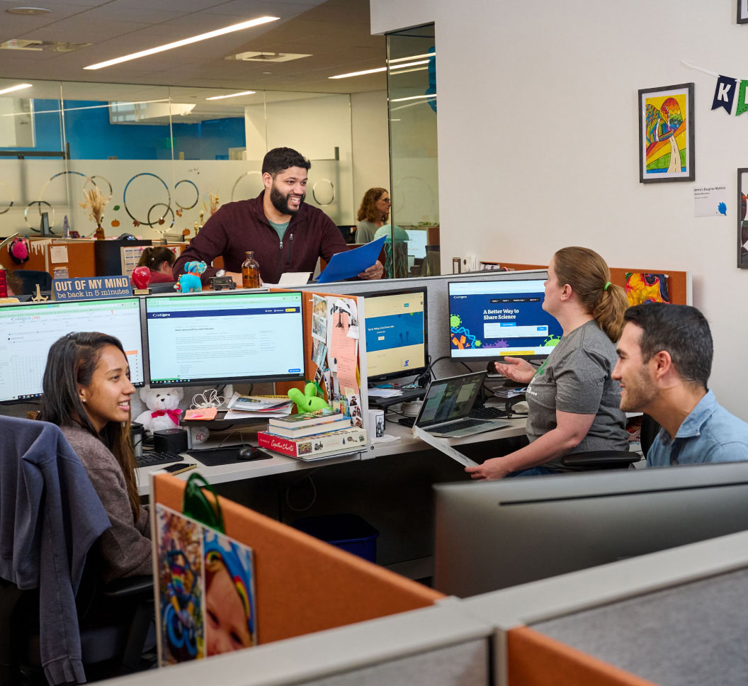 A group of people talking to each other in a colorful office with kid's art displayed on the wall